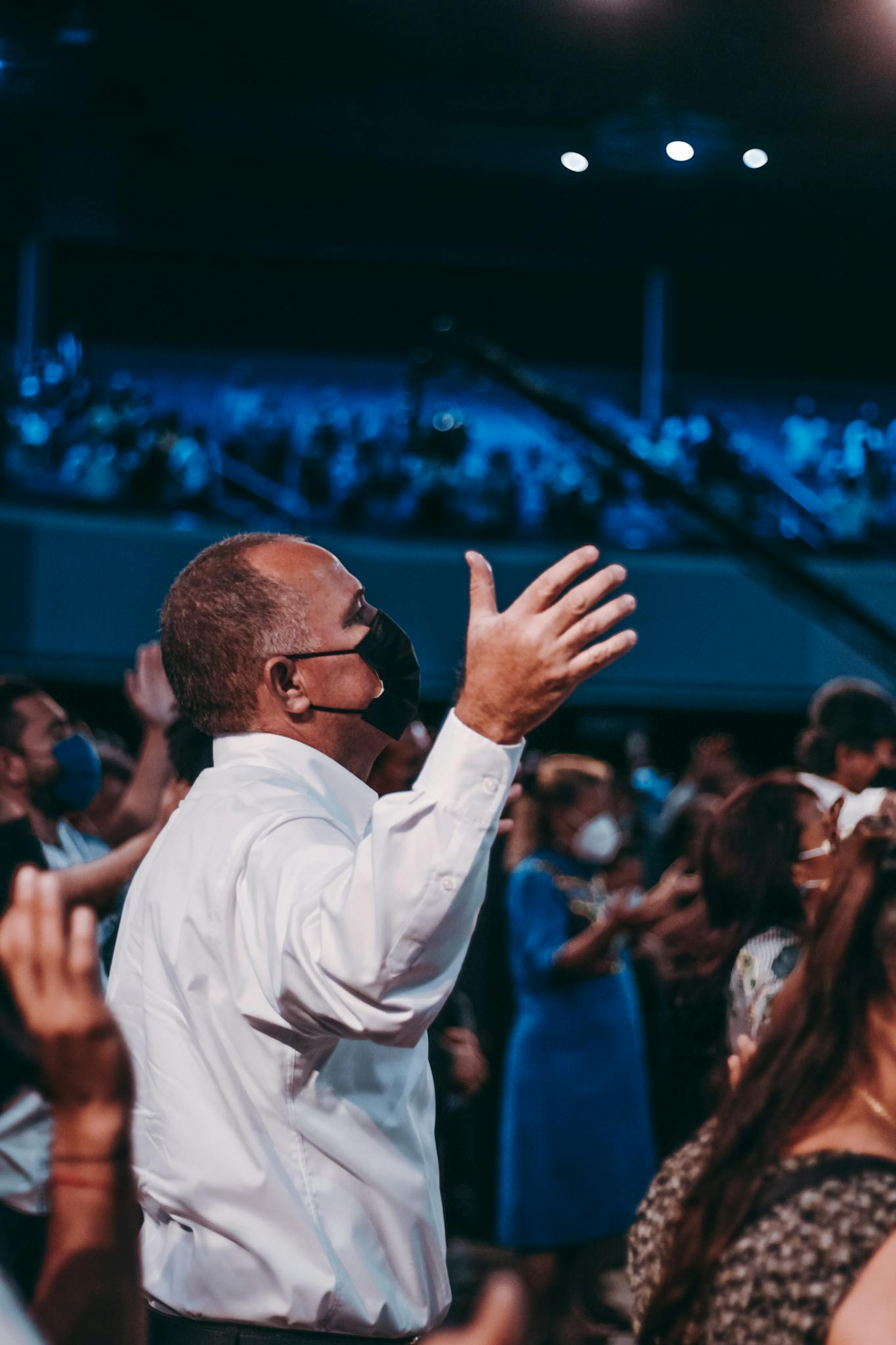 People gathered in an auditorium wearing face masks during a religious worship event, adapting to the new normal.
